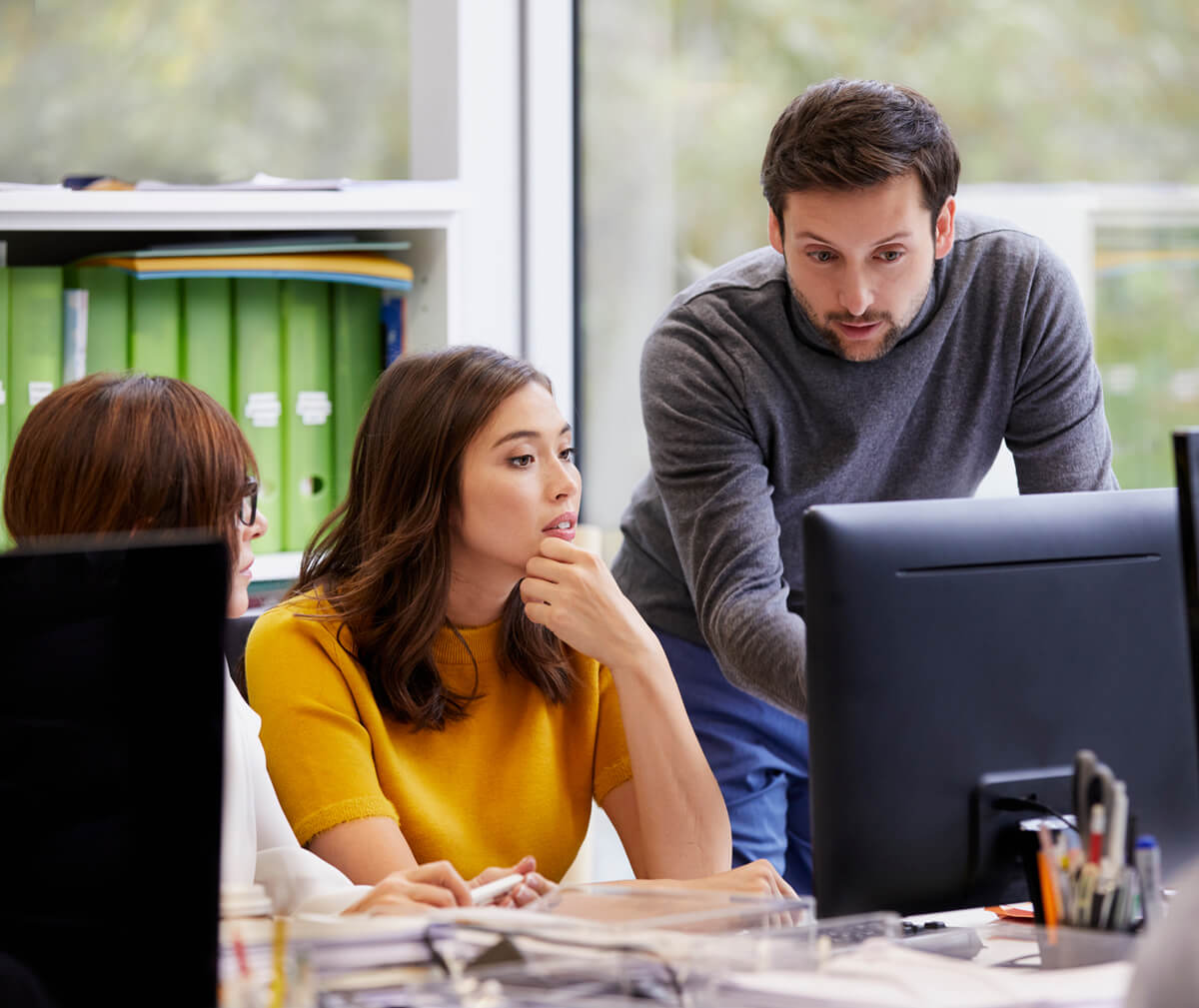 Team members having a discussion, while looking at a computer monitor